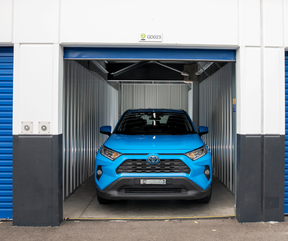 Blue car parked in storage unit with roller door up